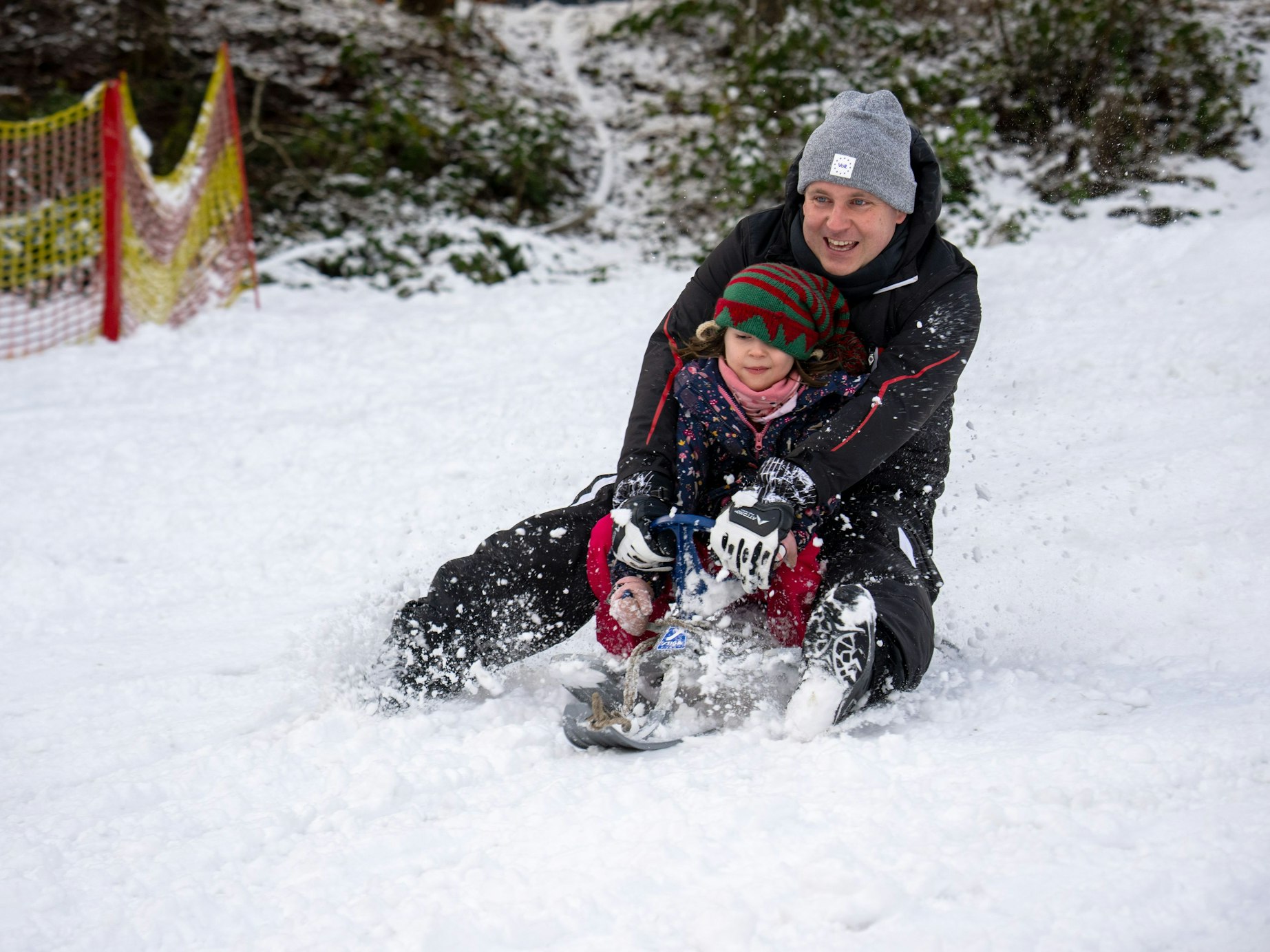 Sascha rodelt mit Tochter Klara Wolfsschlucht den Hang hinab. In der Eifel gab es schon am 2. Januar 2025 Schnee bis in die Niederungen.
