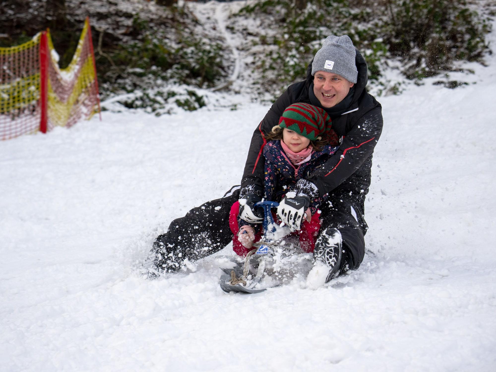 Sascha rodelt mit Tochter Klara Wolfsschlucht den Hang hinab. In der Eifel gab es schon am 2. Januar 2025 Schnee bis in die Niederungen.