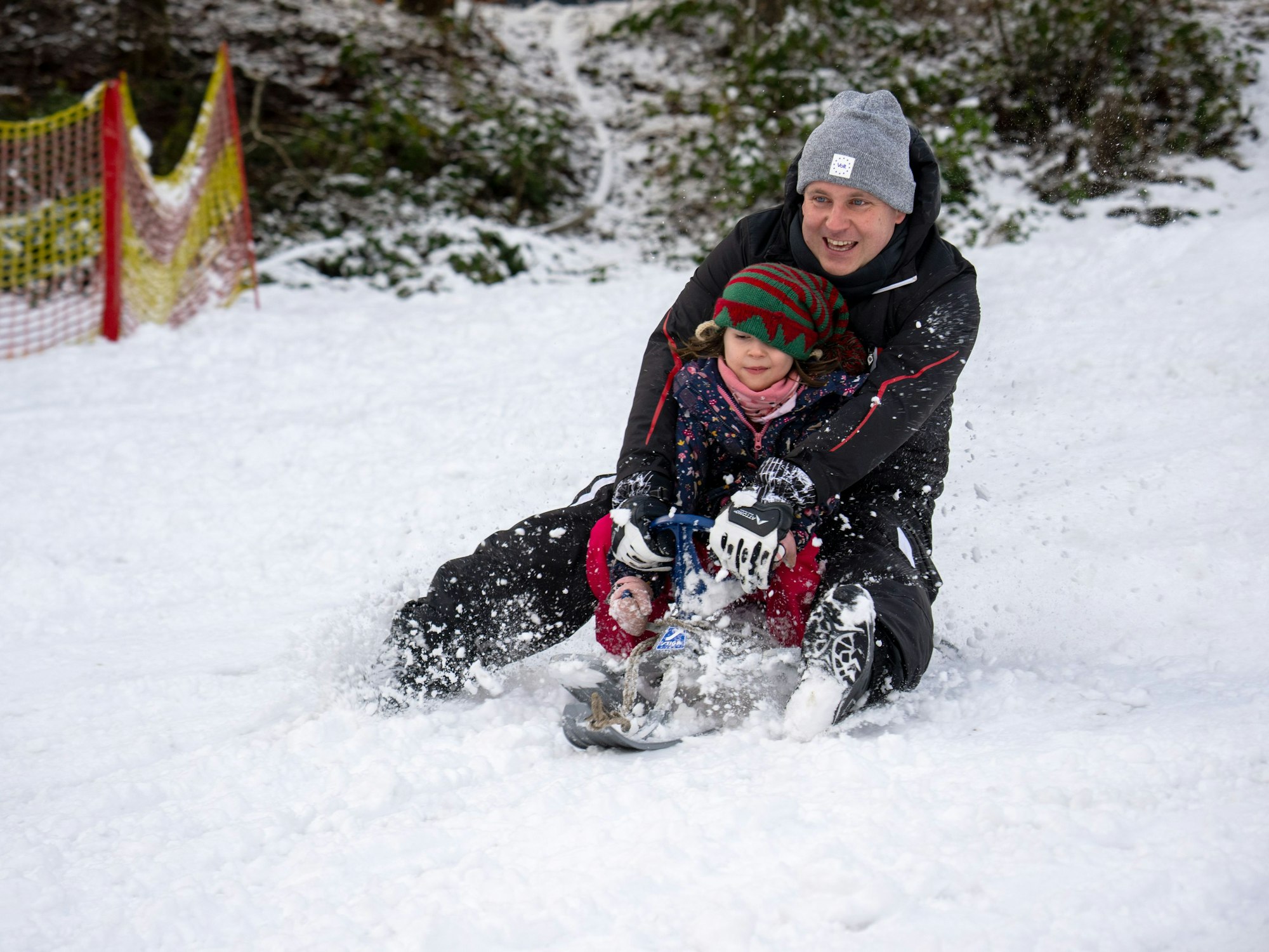 Sascha rodelt mit Tochter Klara Wolfsschlucht den Hang hinab. In der Eifel gab es schon am 2. Januar 2025 Schnee bis in die Niederungen.