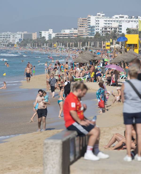 Zahlreiche Strandbesucher sind am Strand von El Arenal auf Mallorca unterwegs.