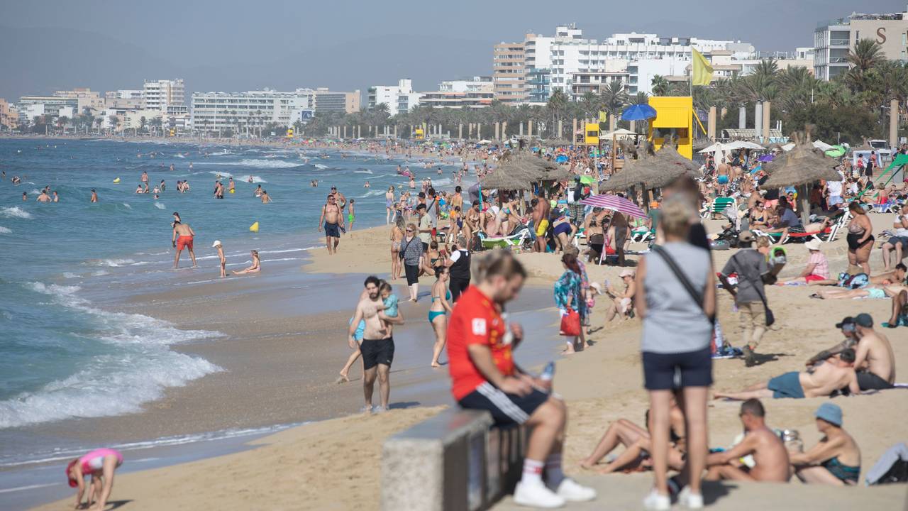 Zahlreiche Strandbesucher sind am Strand von El Arenal auf Mallorca unterwegs.