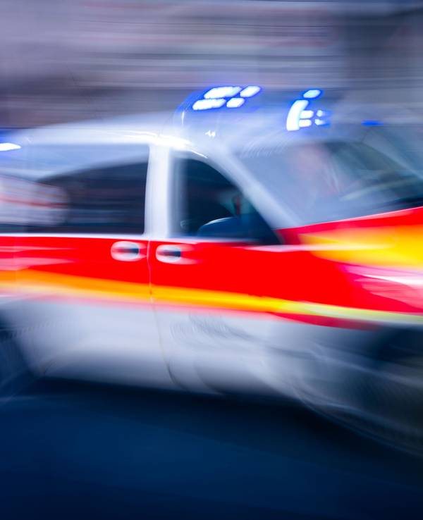 Ein Rettungsfahrzeug ist mit Blaulicht auf einer Straße unterwegs.