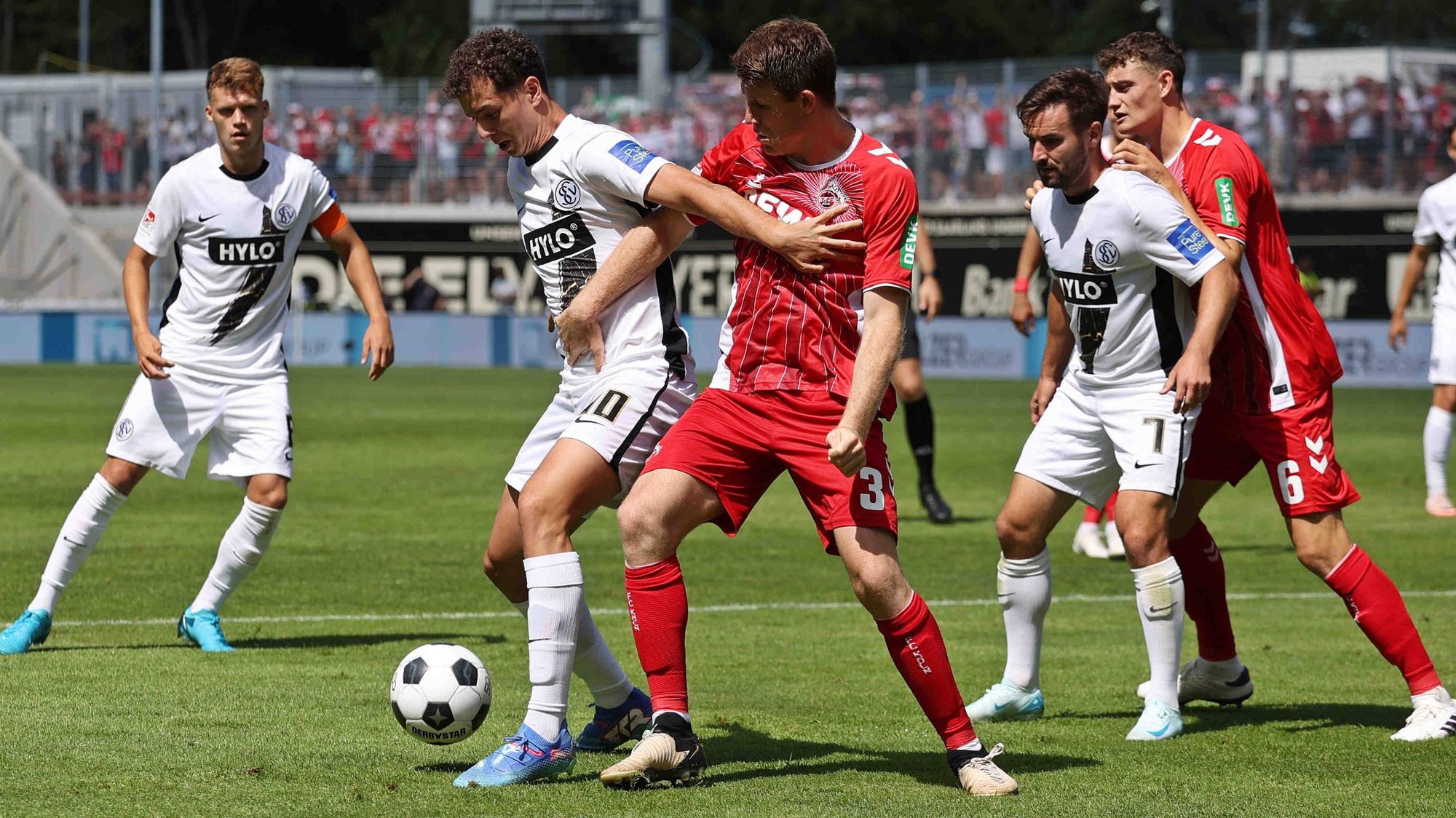 Fisnik Asllani (SV Elversberg) im Duell mit Dominique Heintz (1. FC Köln) um den Ball.