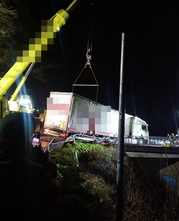 Ein Kran sichert einen auf einer Brücke bei Gummersbach festgefahrenen Lastwagen. Der Lkw droht auf die Bahngleise zu stürzen.