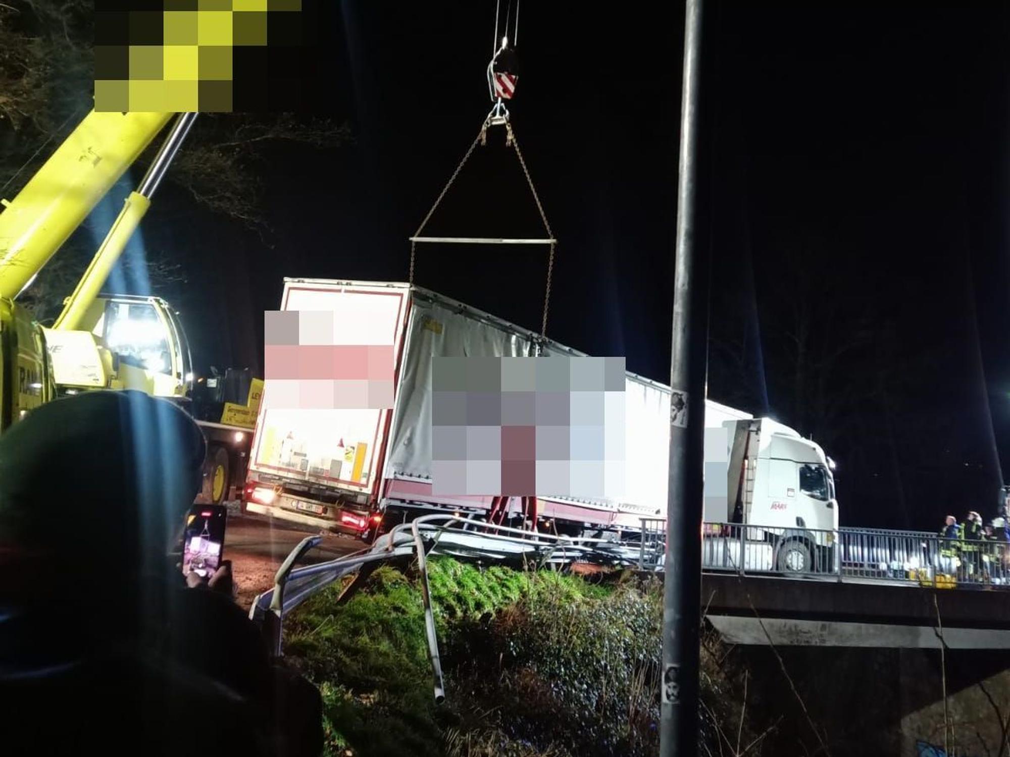 Ein Kran sichert einen auf einer Brücke bei Gummersbach festgefahrenen Lastwagen. Der Lkw droht auf die Bahngleise zu stürzen.