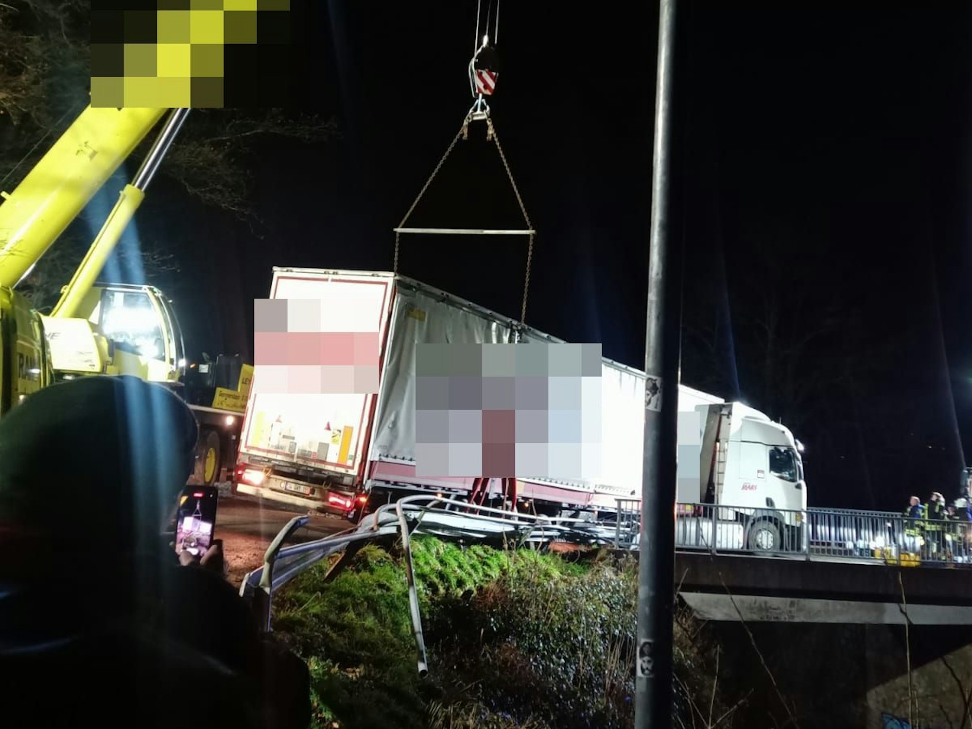 Ein Kran sichert einen auf einer Brücke bei Gummersbach festgefahrenen Lastwagen. Der Lkw droht auf die Bahngleise zu stürzen.
