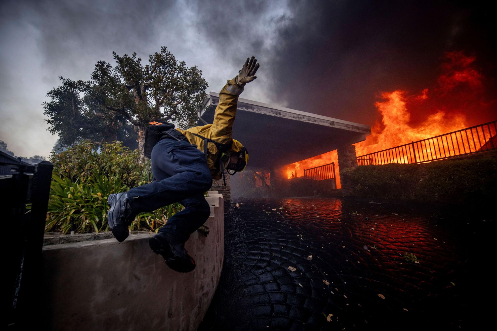 Ein Feuerwehrmann springt über einen Zaun.