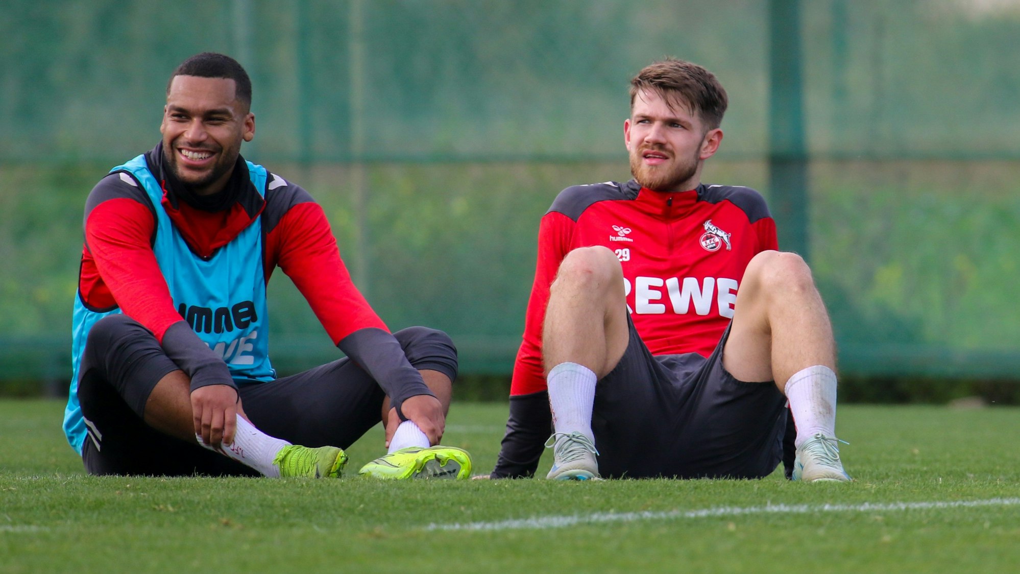 Linton Maina und Jan Thielmann sitzen im FC-Trainingslager auf dem Trainingsplatz.