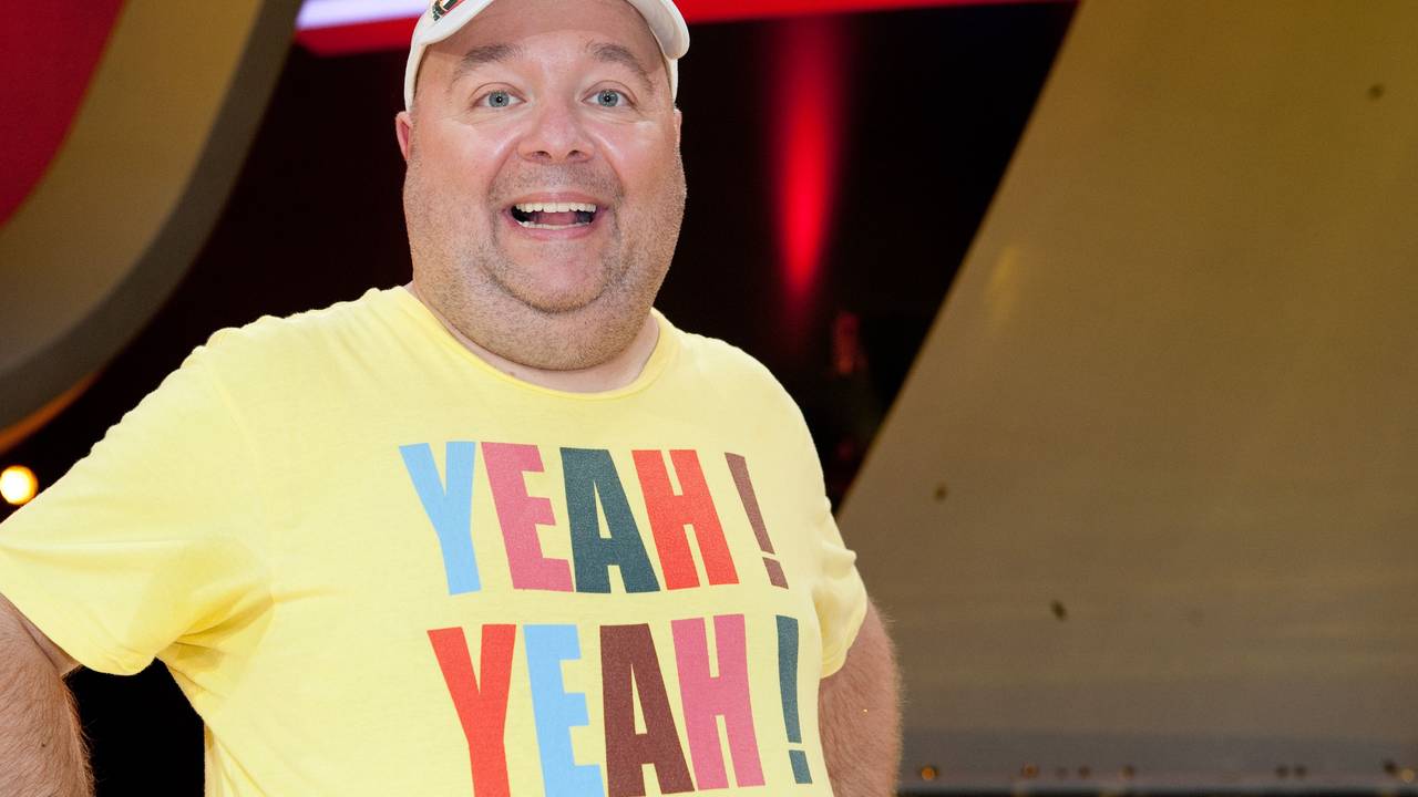 Der Moderator und Entertainer Dirk Bach bei einer Sendung in einem gelben Shirt und mit Mütze.
