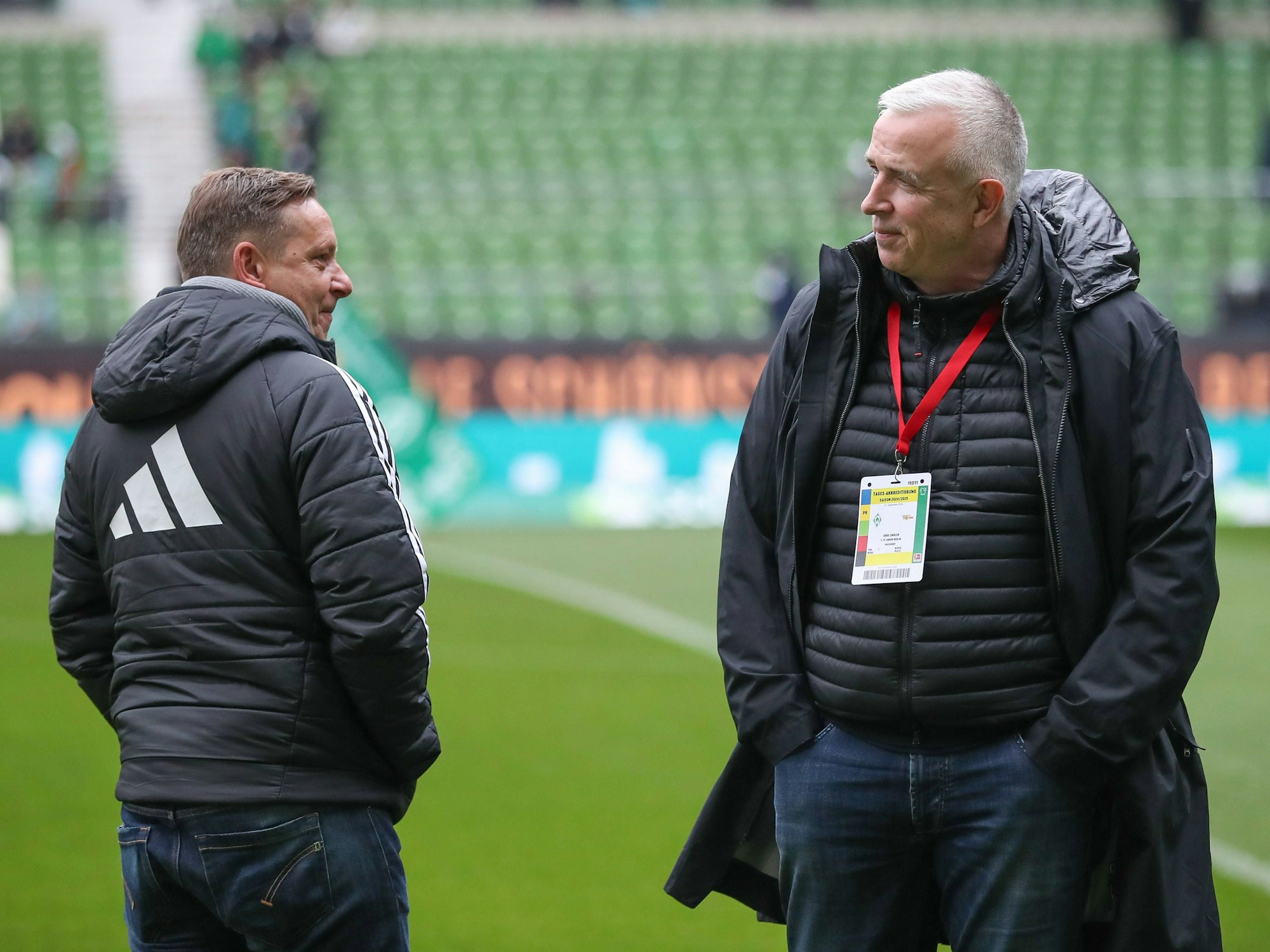 Dirk Zingler spricht auf dem Rasen mit Horst Heldt.