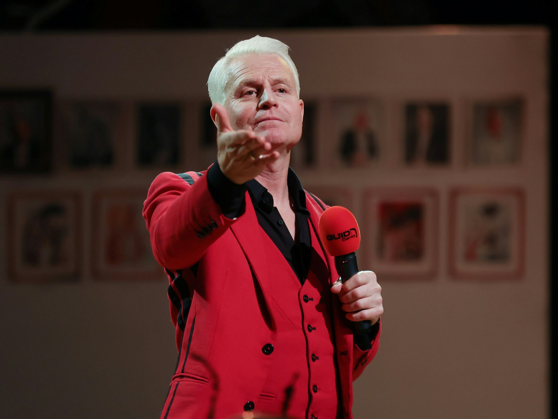 Guido Cantz in seinem typischen roten Sakko auf der Bühne bei einer Karnevalssitzung in Köln.