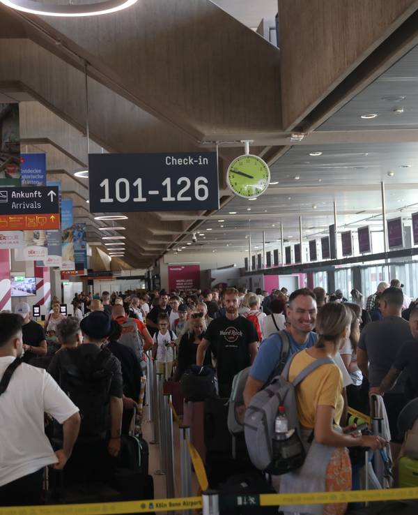 Menschen stehen am Flughafen Köln/Bonn in der Schlange vor dem Check-in.