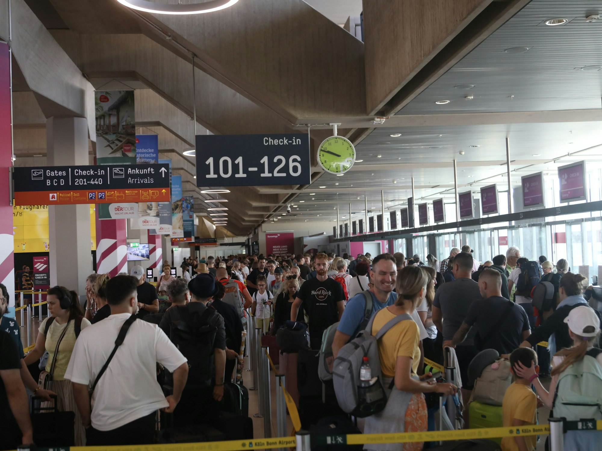 Menschen stehen am Flughafen Köln/Bonn in der Schlange vor dem Check-in.
