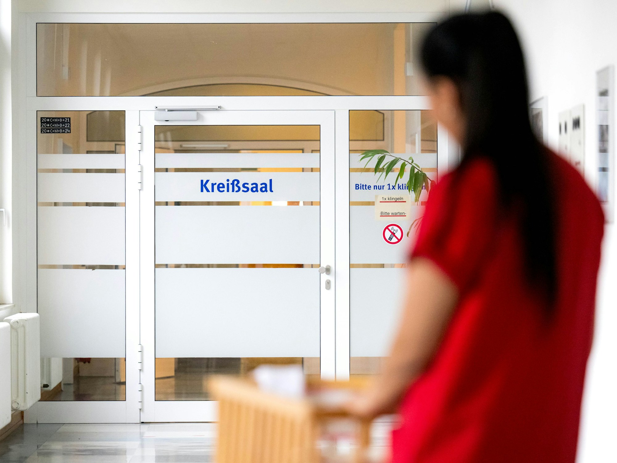 Eine Hebamme schiebt ein Bett mit einem Säugling zum Kreißsaal.