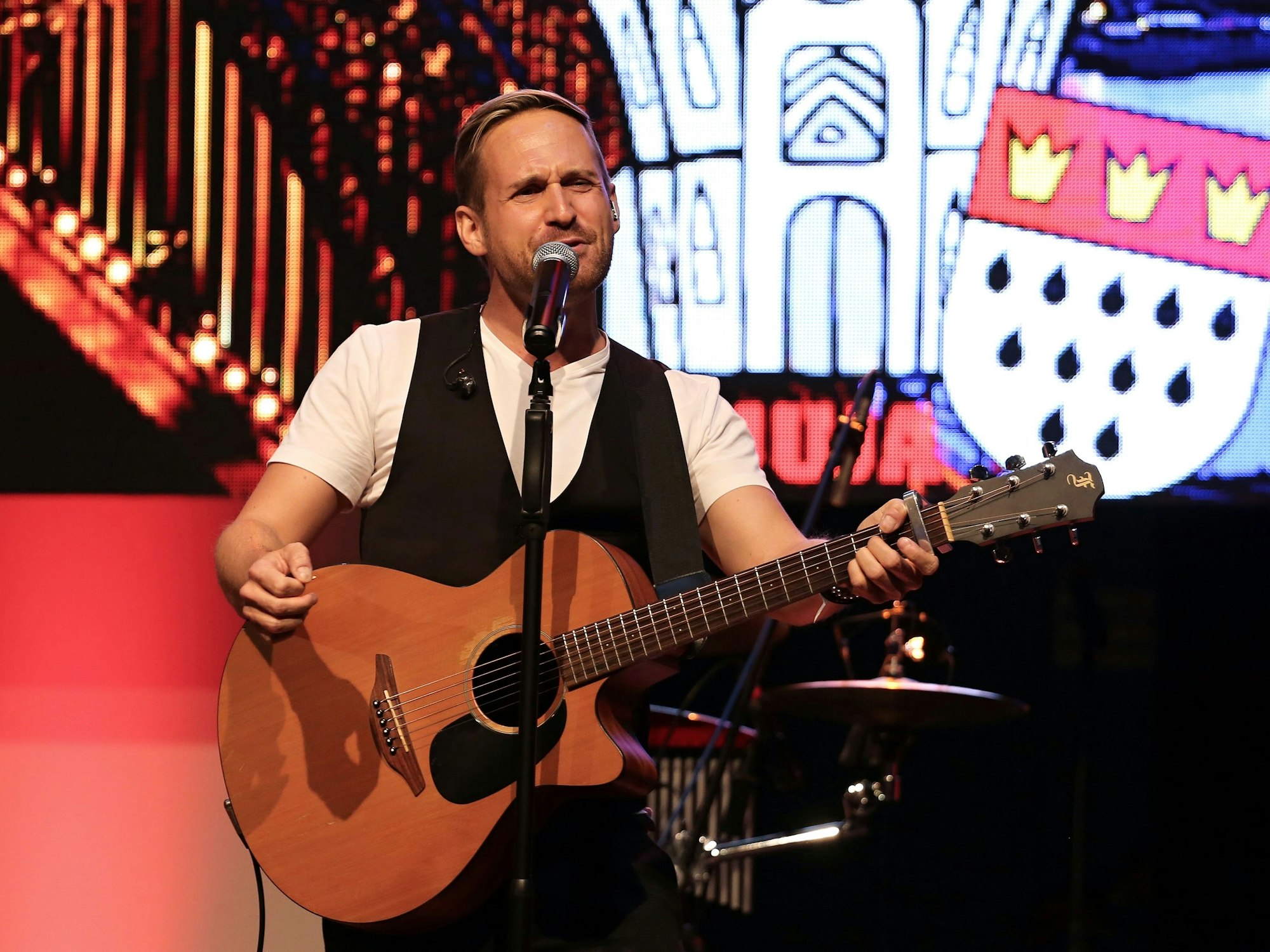 Philipp Godart steht mit Gitarre auf der Bühne.