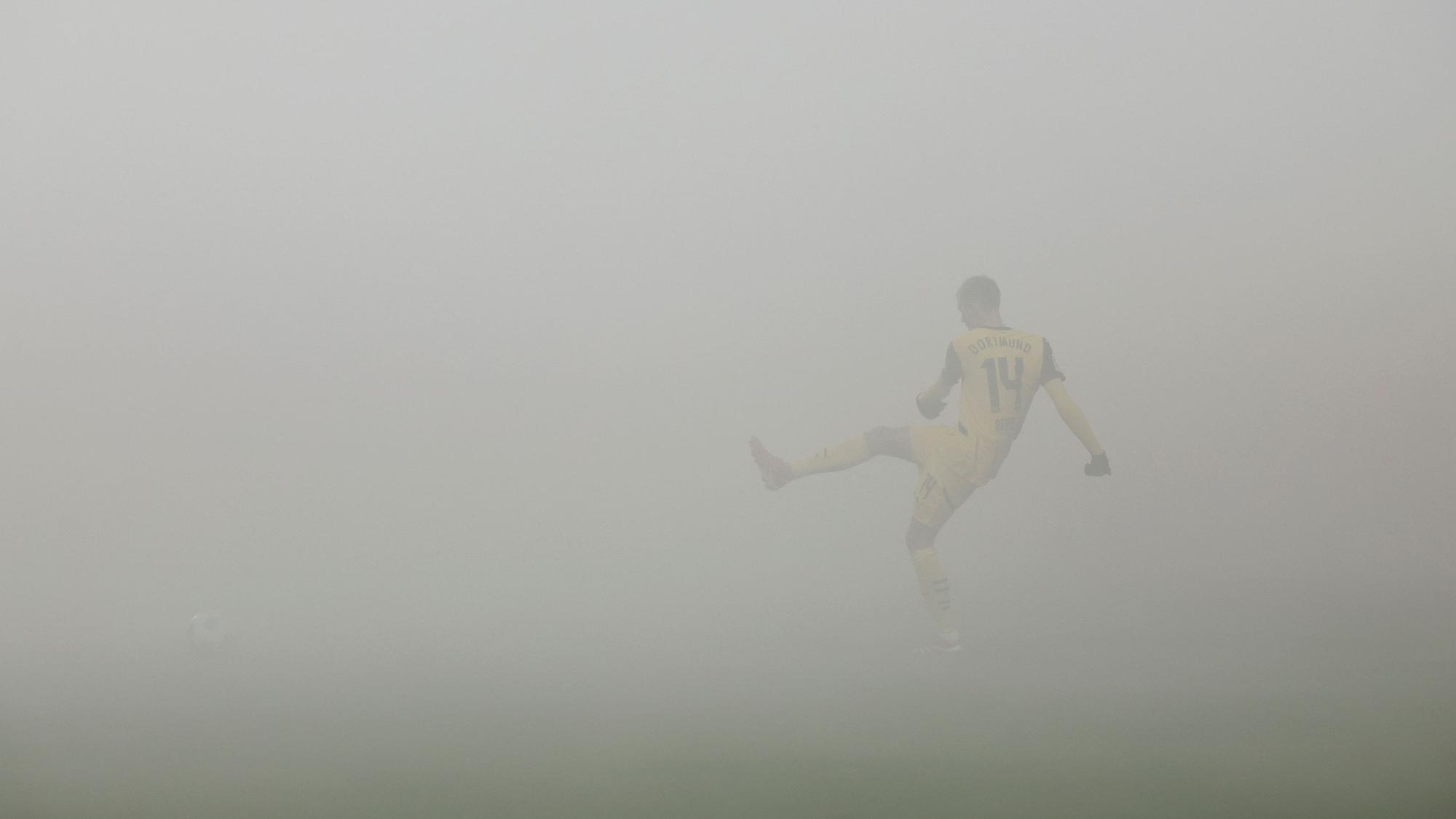 Dortmund-Profi Maximilian Beier passt den Ball im Auswärtsspiel bei Holstein Kiel. Der Platz ist in dicken Nebel gehüllt.