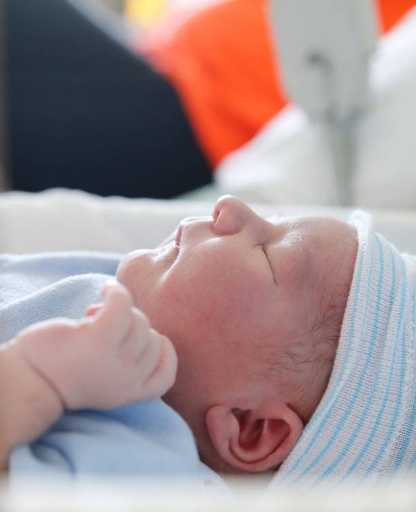 Baby liegt im Bett auf einer Geburtenstation.