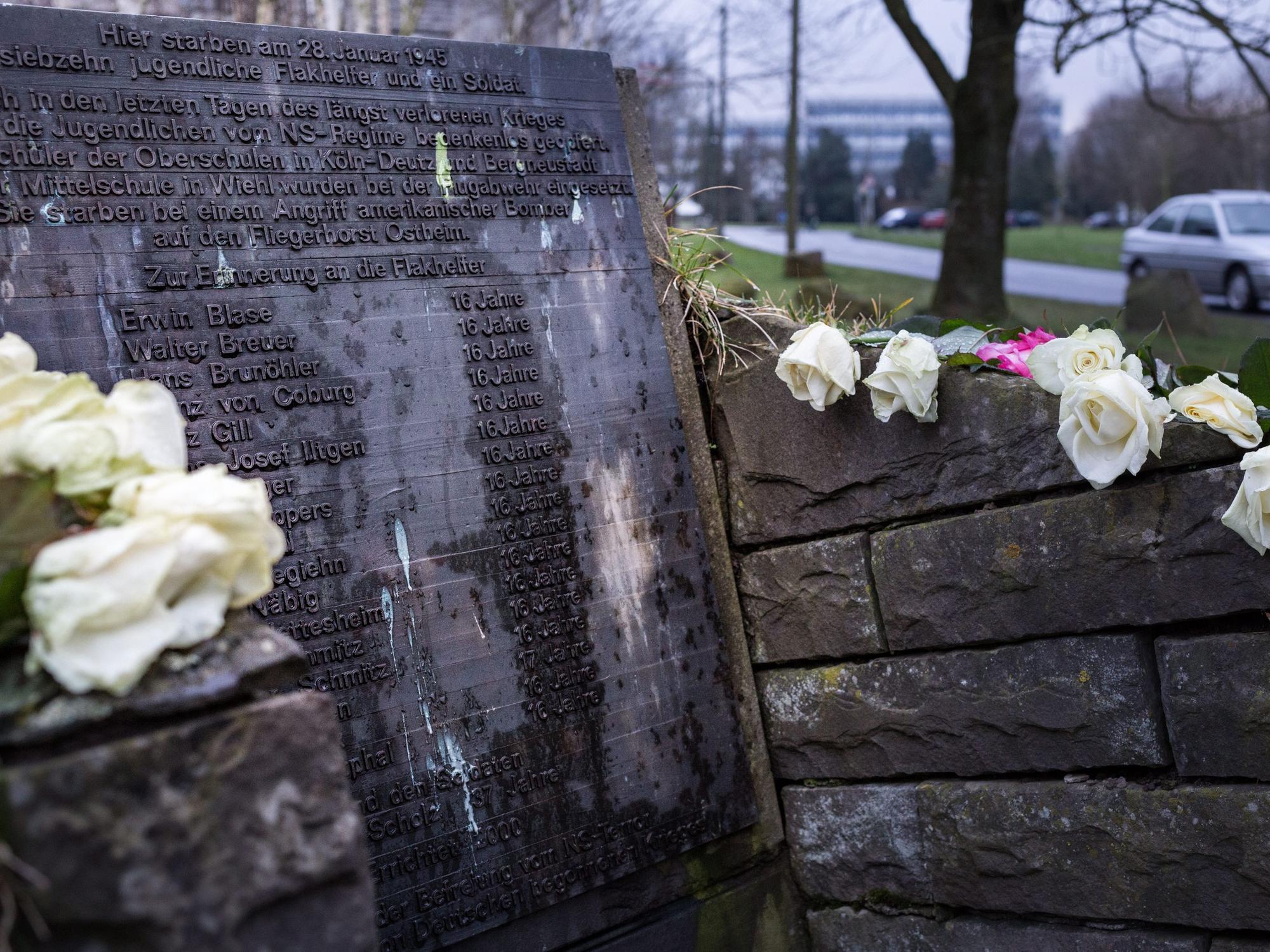 Weisse Rosen liegen auf einem Denkmal.