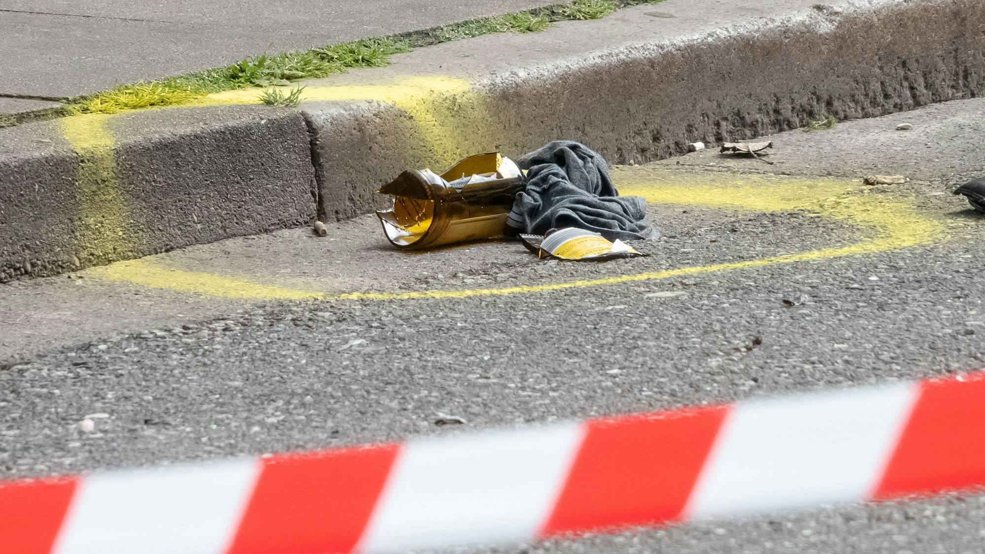 Ein Molotowcocktail liegt hinter einem Absperrband der Polizei auf dem Boden.