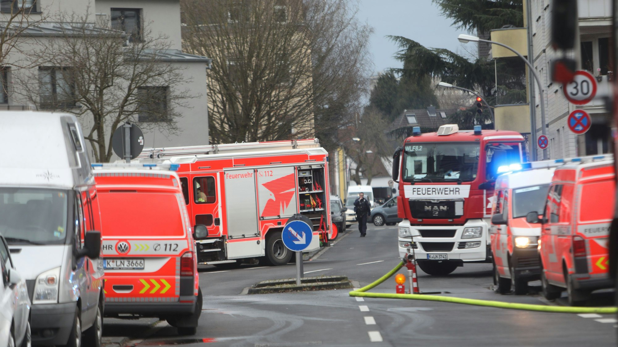 Auf einer Straße stehen zwei Fahrzeuge der Feuerwehr und drei des Rettungsdienstes, auf der Fahrbahn liegt ein Löschschlauch.