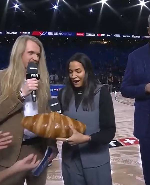 Die neben Icke Dommisch stehende TV-Expertin Ireti Amojo bekommt ein Riesen-Croissant überreicht.