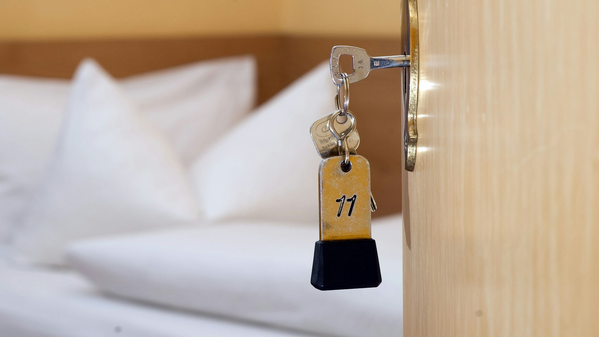 Ein Hotel-Zimmerschlüssel hängt in einem Türschloss.
