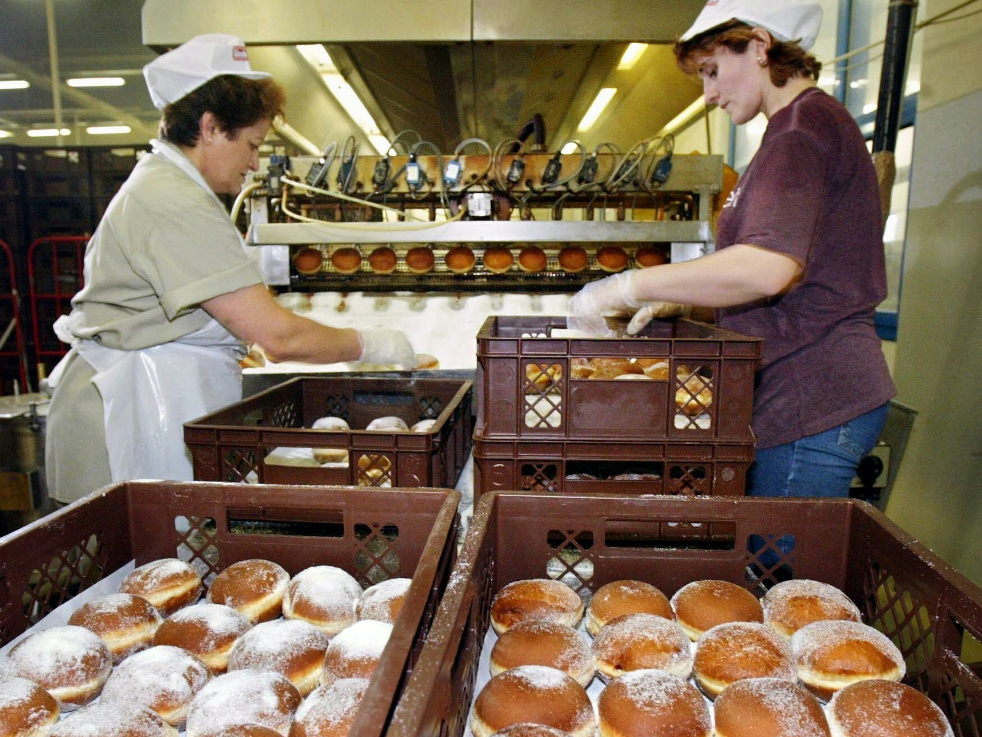 Zwei Arbeiterinnen packen am Donnerstag (19.02.2004) in der Glockenbrot-Bäckerei in Frankfurt frisch gebackene Kreppel,