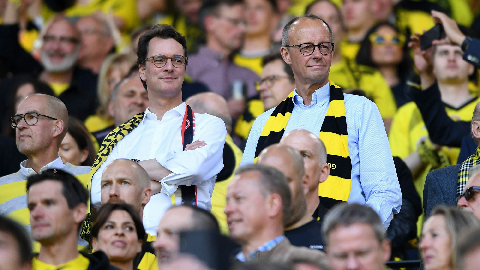 Friedrich Merz steht mit BVB-Schal auf der Tribüne in Dortmund.