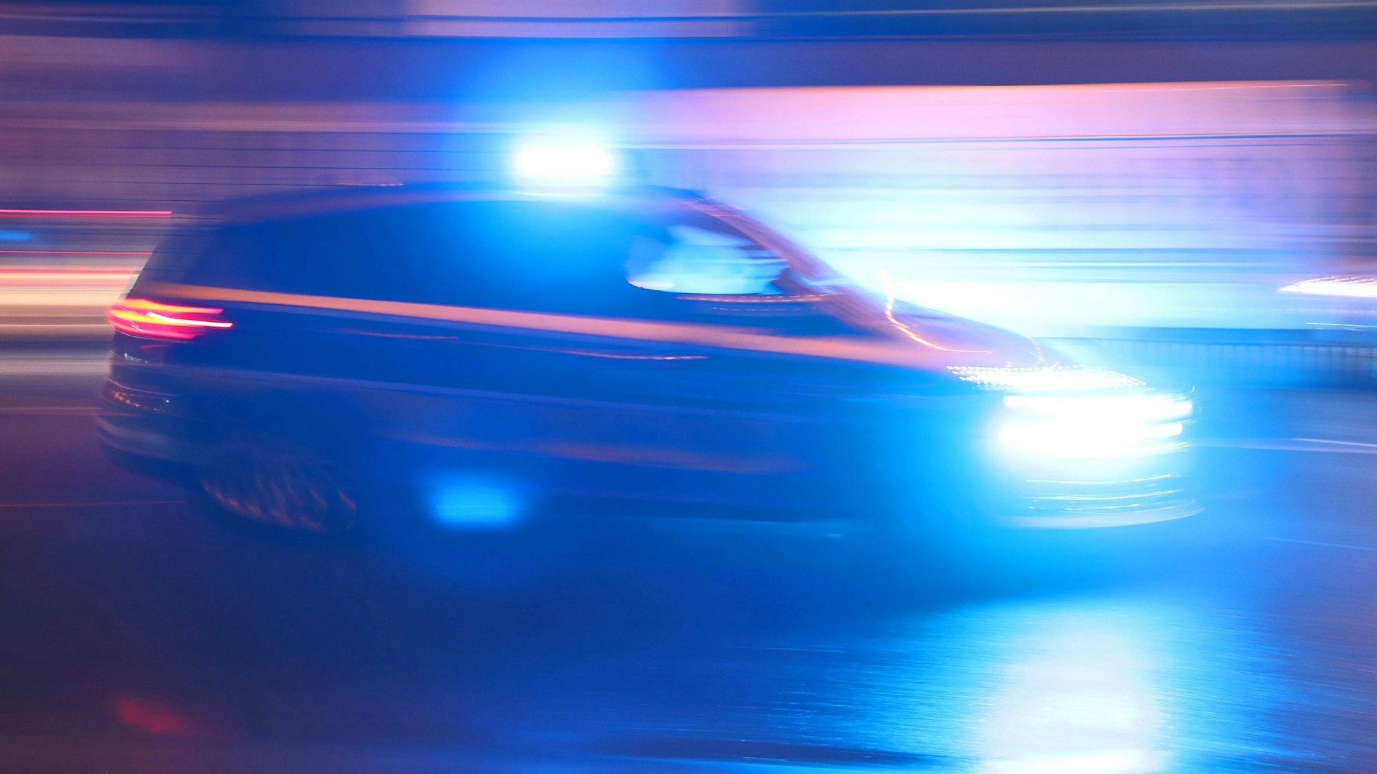 Ein Einsatzfahrzeug der Polizei fährt mit Blaulicht durch eine Kölner Straße zu einem Einsatz (Symbolbild).