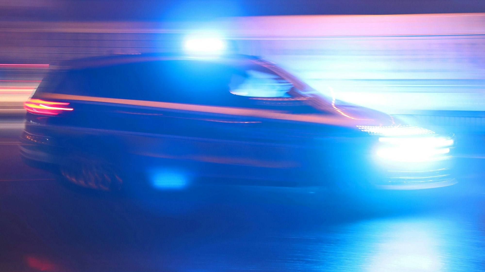 Ein Einsatzfahrzeug der Polizei fährt mit Blaulicht durch eine Kölner Straße zu einem Einsatz.