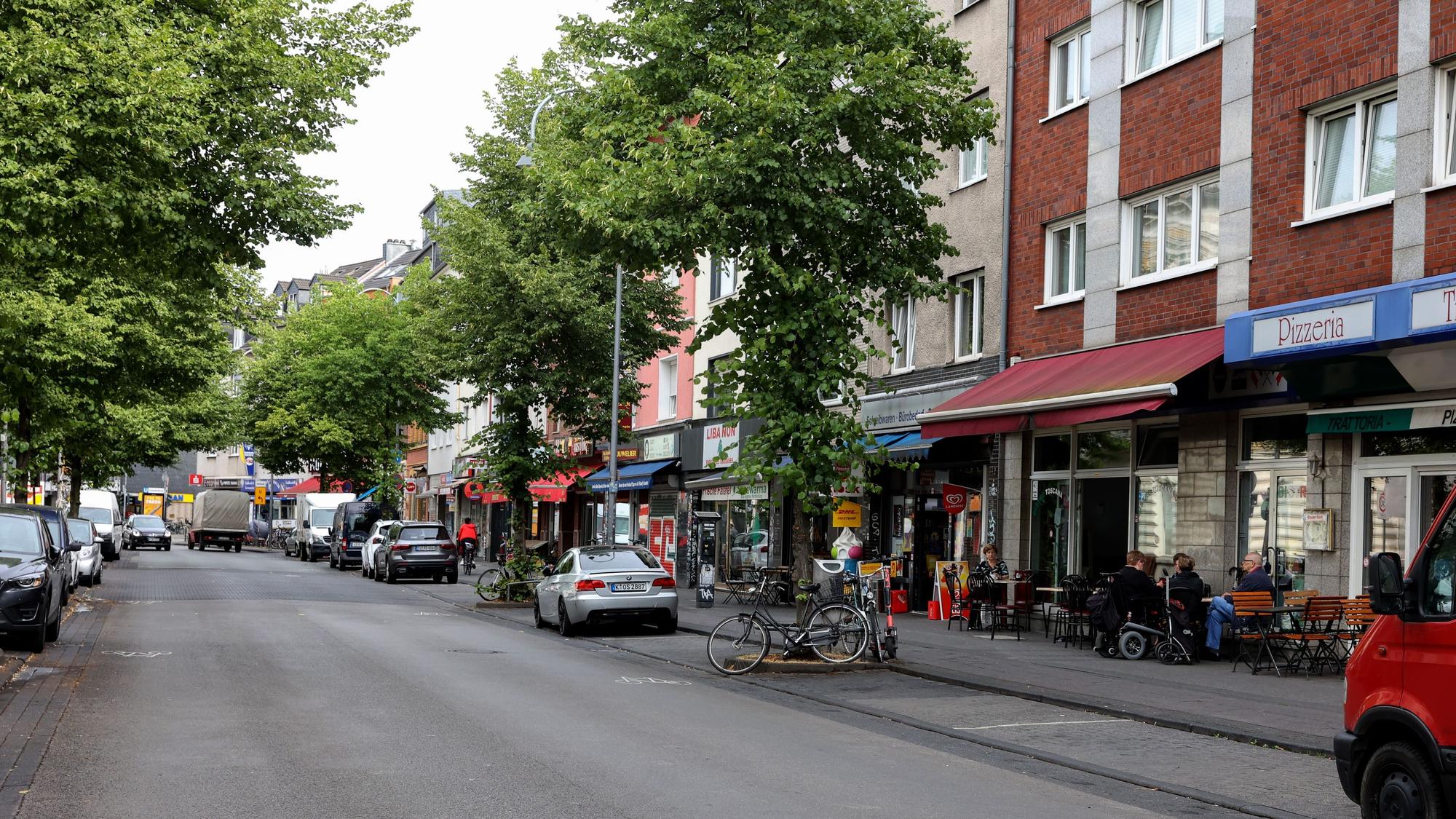 Autos auf der Venloer Straße in Köln, an den Straßenrändern sind Cafés und andere Außengastro zu sehen.