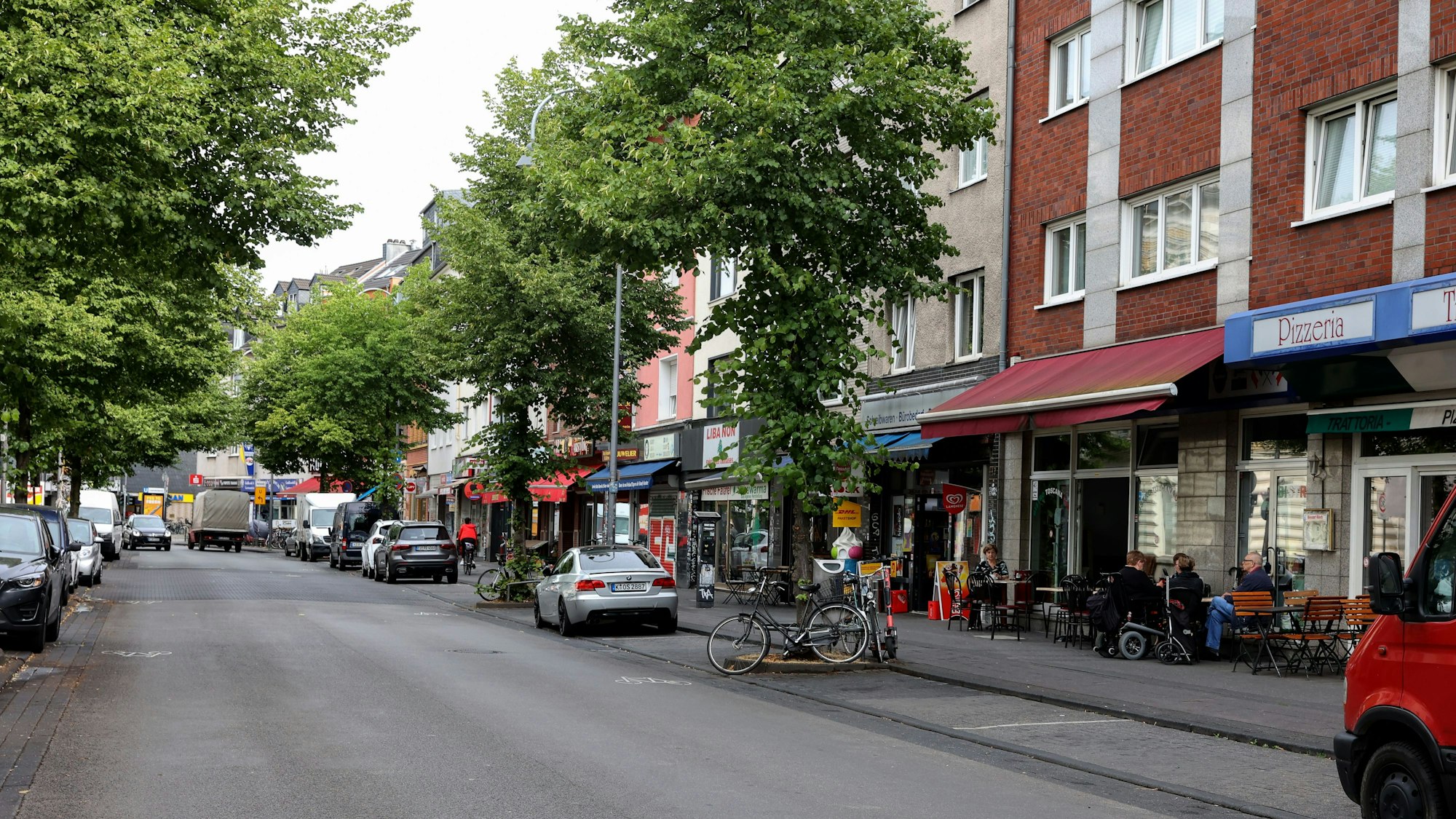 Autos auf der Venloer Straße in Köln, an den Straßenrändern sind Cafés und andere Außengastro zu sehen.