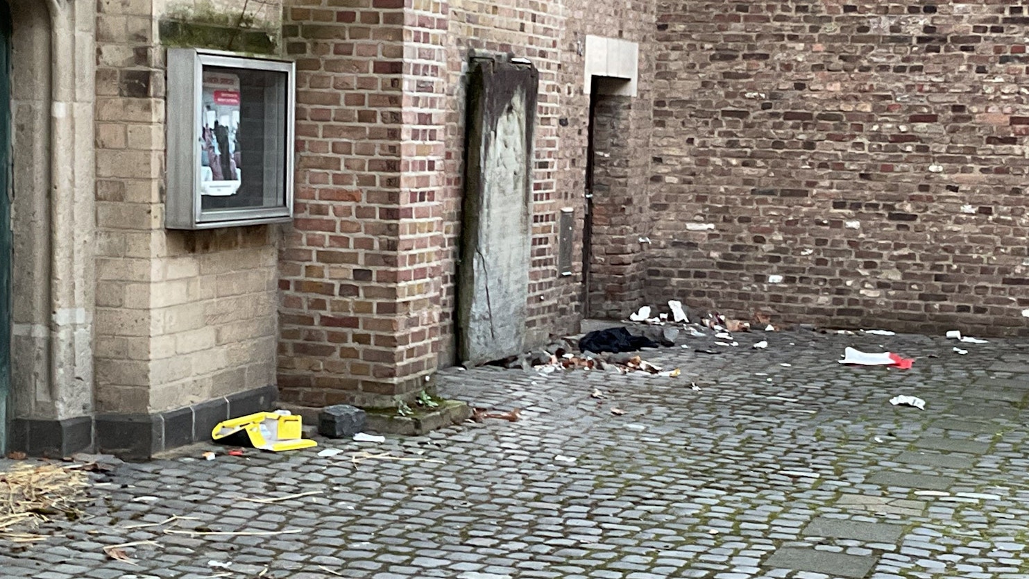 An den Mauern einer Kirche liegen leere Verpackungen und anderer Müll.