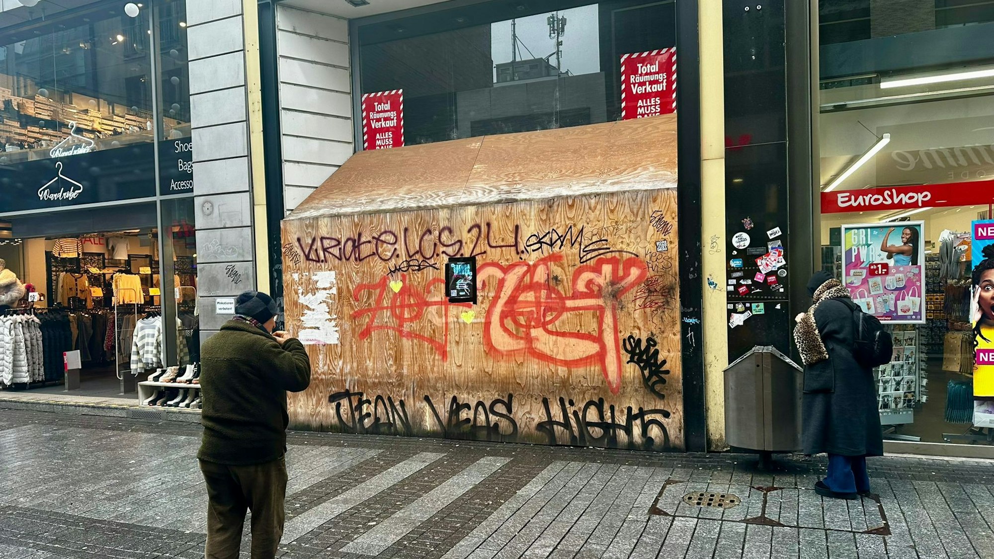 Ein Euroshop befindet sich neben einem leeren Ladenlokal, dessen Eingang mit vollgesprayten Brettern verbarrikadiert wurde.
