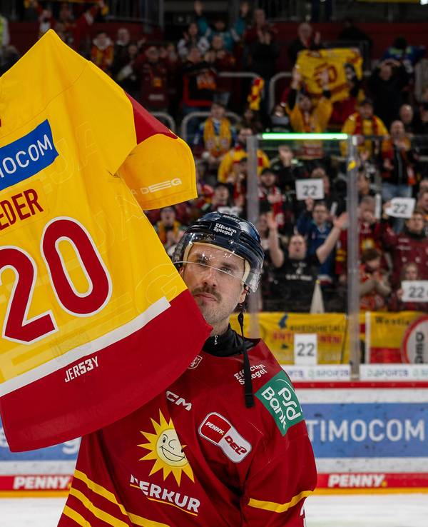 DEG-Profi Brendan O'Donnell hält ein DEG-Trikot des verstorbenen Tobias Eder mit der Nummer 20 hoch.