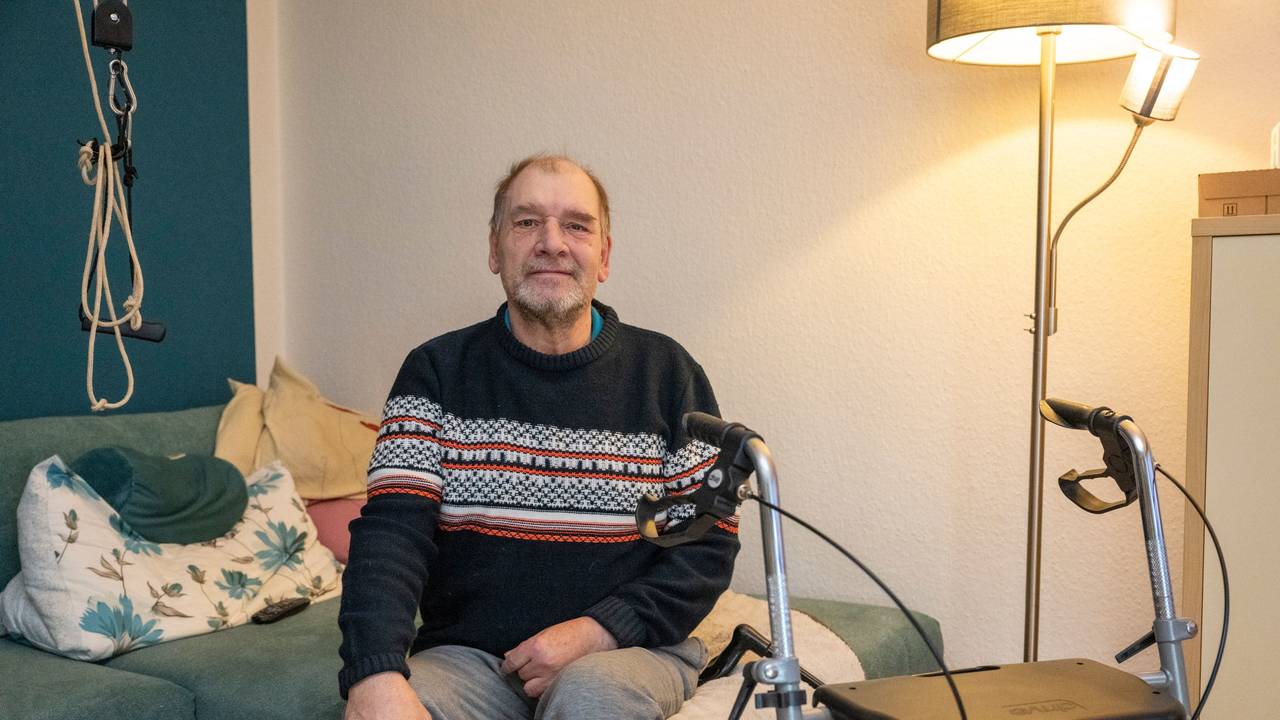 Ein Mann sitzt auf einem Sofa.