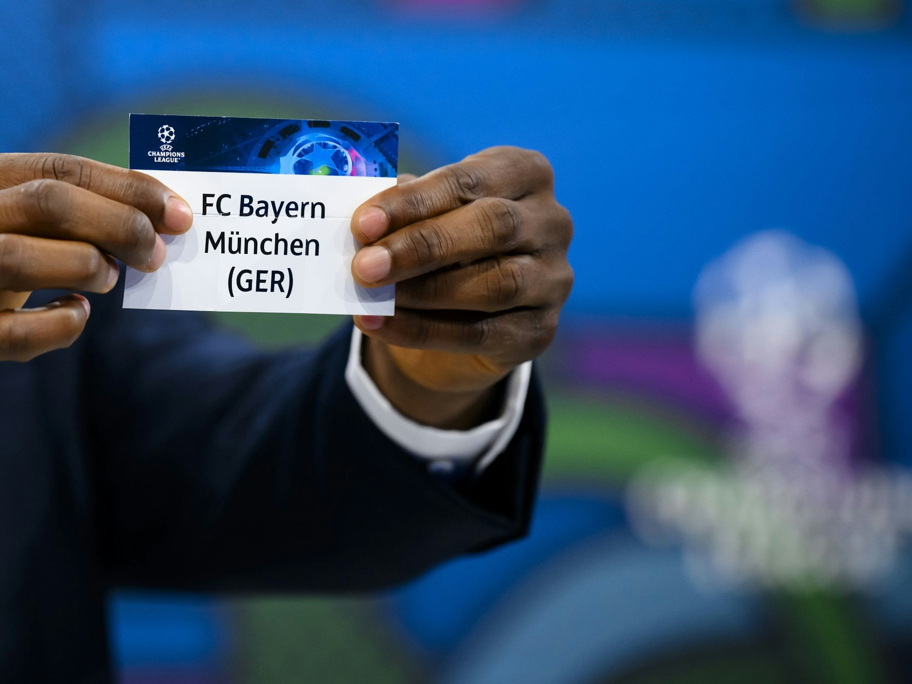 John Obi Mikel zeigt das Los des FC Bayern München.