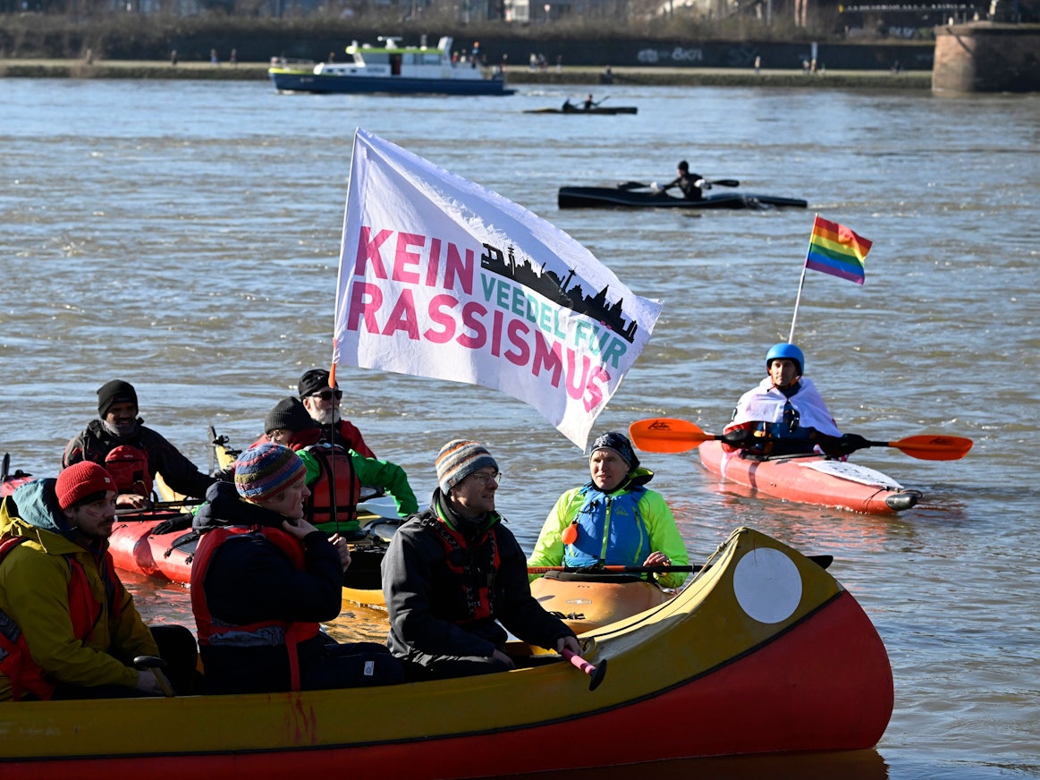 Auf einem Kanu weht eine Fahne mit der Aufschrift „Kein Veedel für Rassismus“.