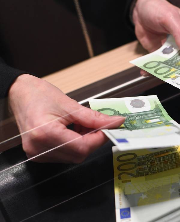 Eine Frau lässt sich in einer Bankfiliale am Schalter Bargeld auszahlen.(Symbolbild)