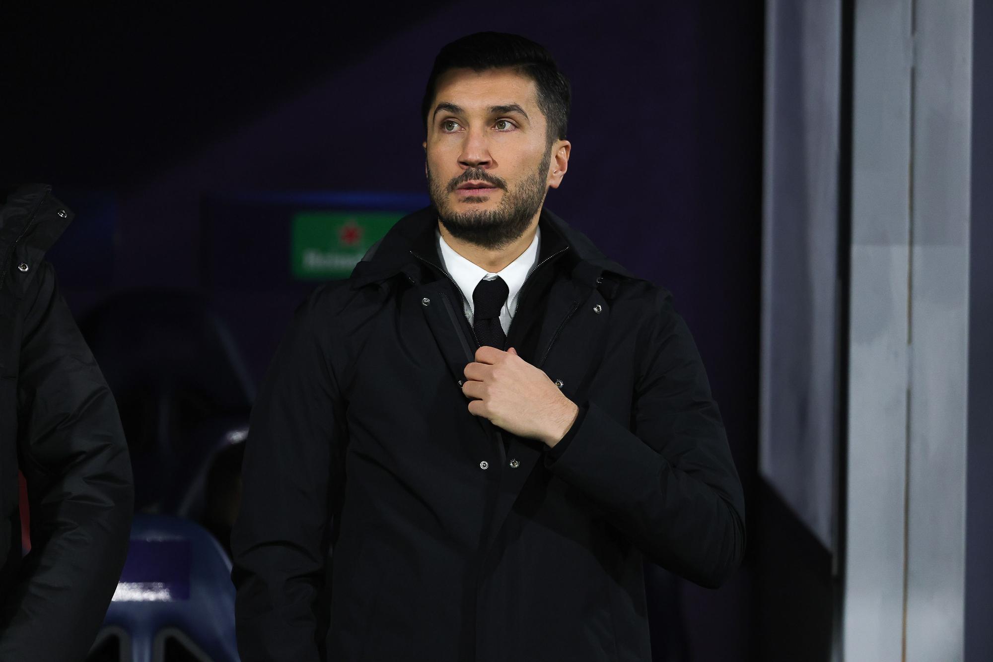 Dortmunds Trainer Nuri Sahin fasst im Stadion an seine Krawatte.