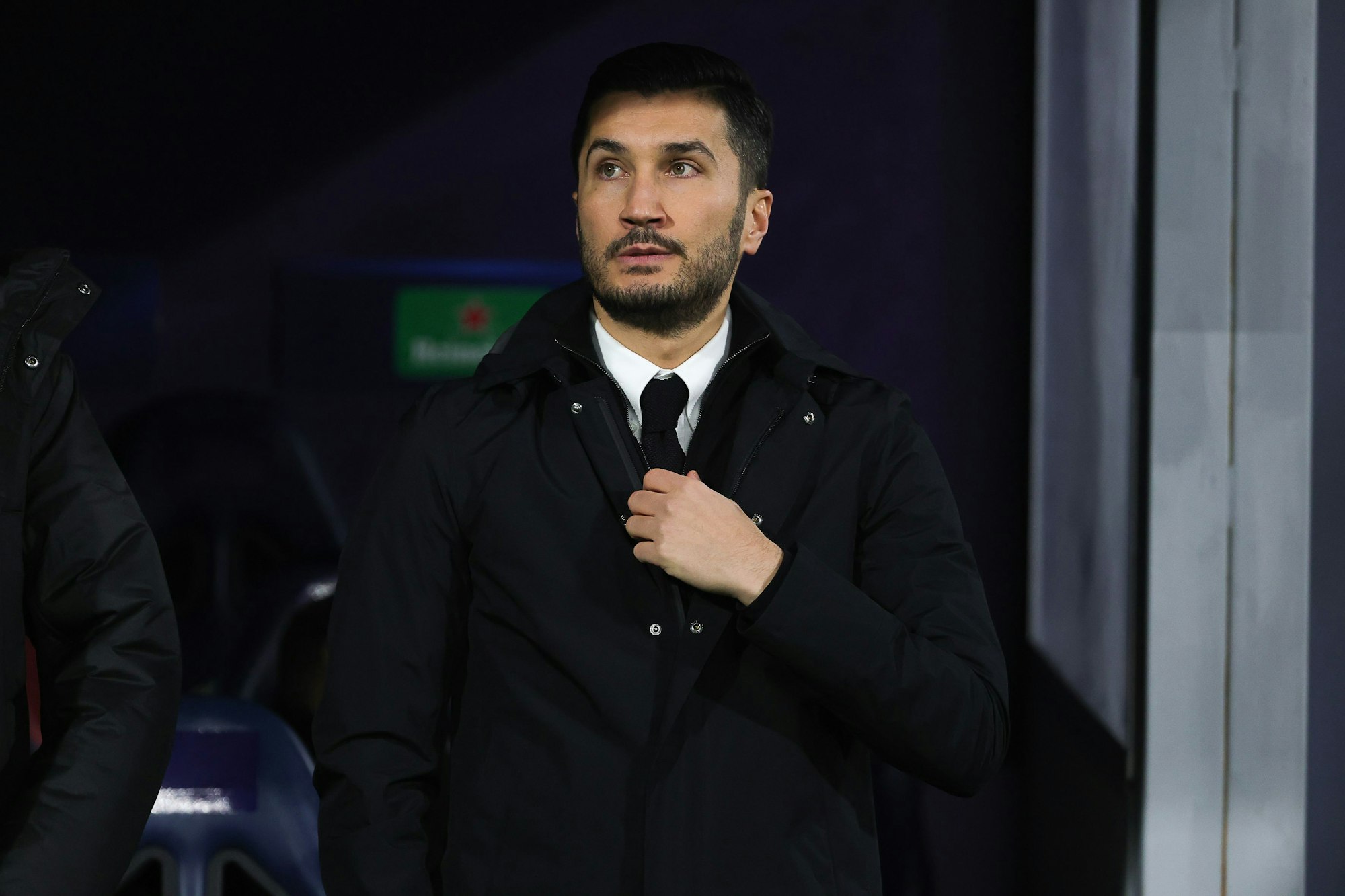 Dortmunds Trainer Nuri Sahin fasst im Stadion an seine Krawatte.