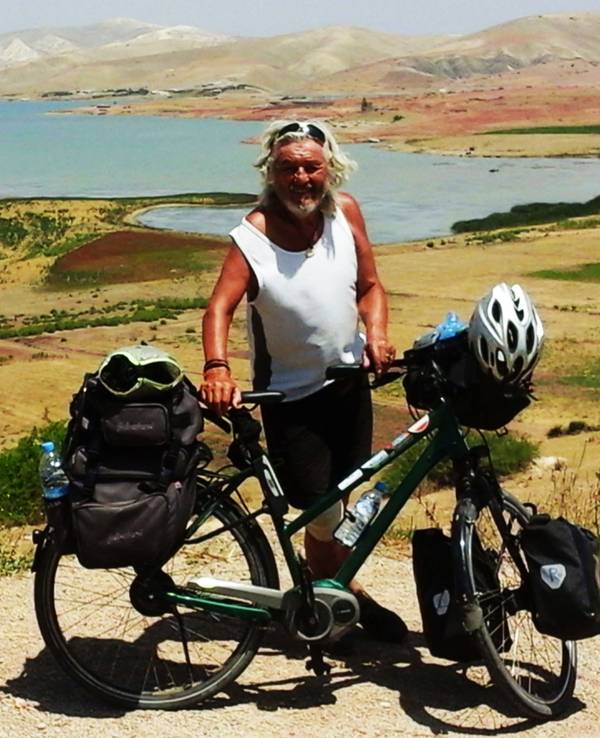 Wolfgang Hollmer mit seinem Fahrrad vor einem großen Landschaft in Marokko.