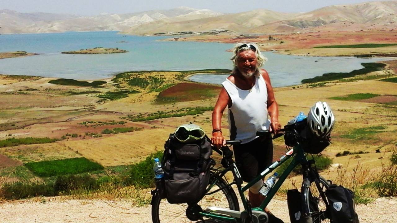 Wolfgang Hollmer mit seinem Fahrrad vor einem großen Landschaft in Marokko.
