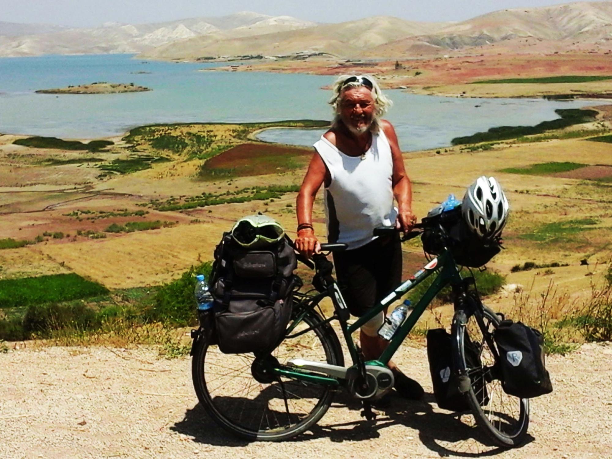 Wolfgang Hollmer mit seinem Fahrrad vor einem großen Landschaft in Marokko.