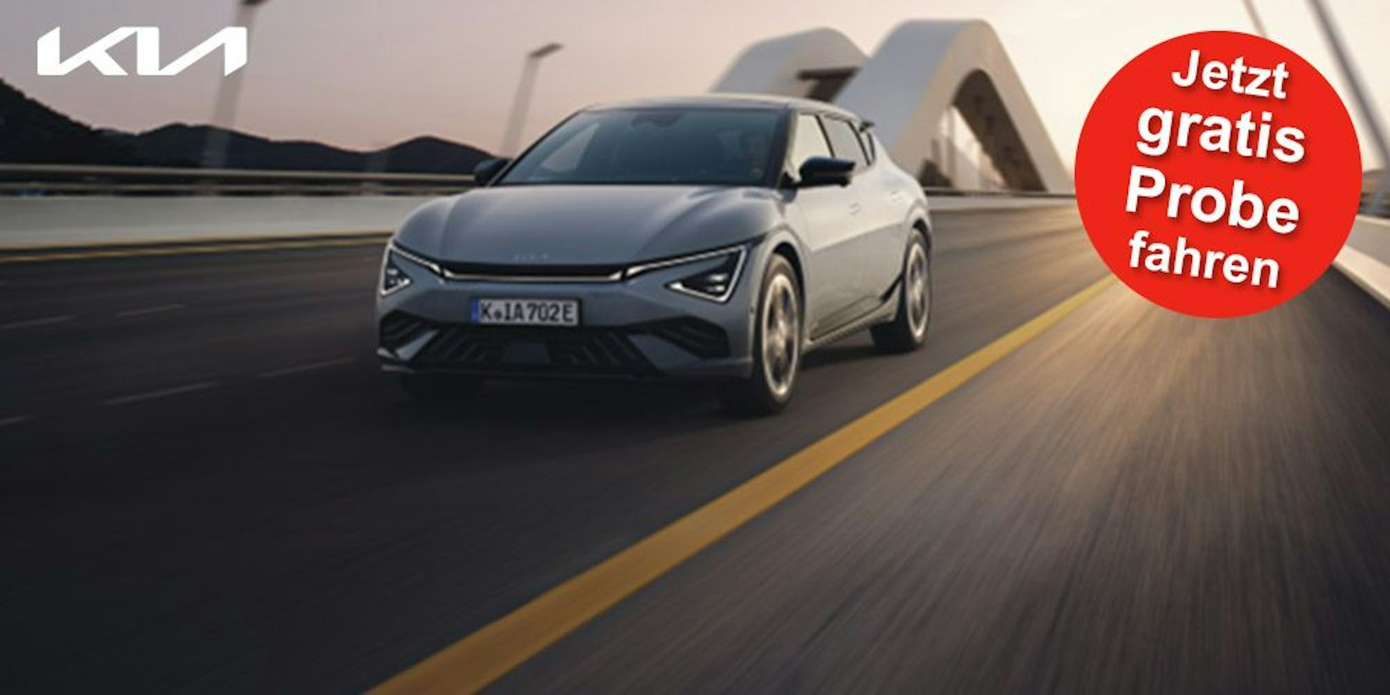 Ein grauer Kia EV6 GT-line fährt in der Abenddämmerung schnell auf einer Autobahn.