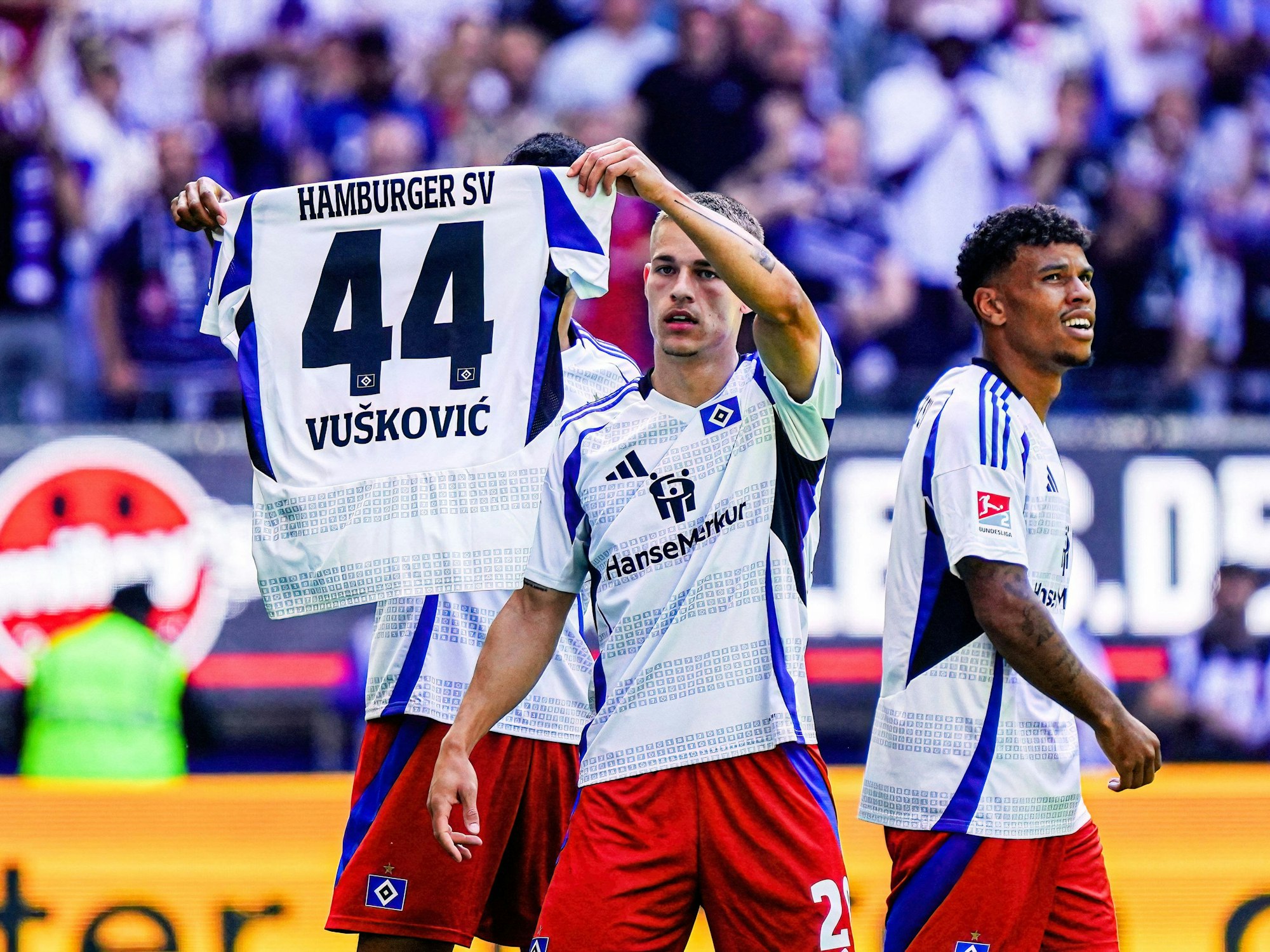 Die HSV-Profis Miro Muheim (r.) und Robert Glatzel halten das Trikot ihres gesperrten Team-Kollegen Mario Vuskovic in die Höhe. (31. August 2024)