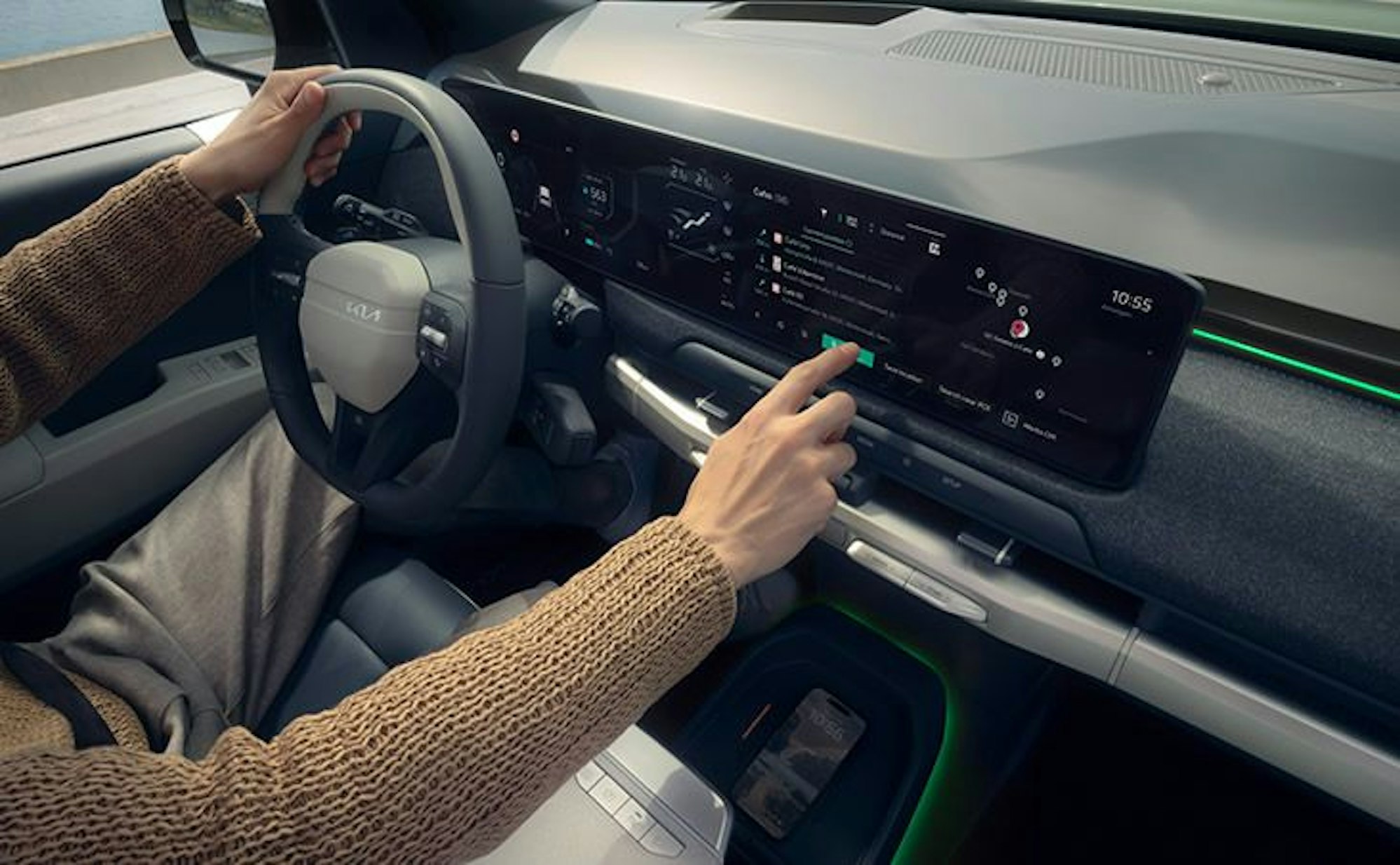 Innenraum des Kia EV3 mit Fahrer am Lenkrad, der am Display Einstellungen vornimmt.