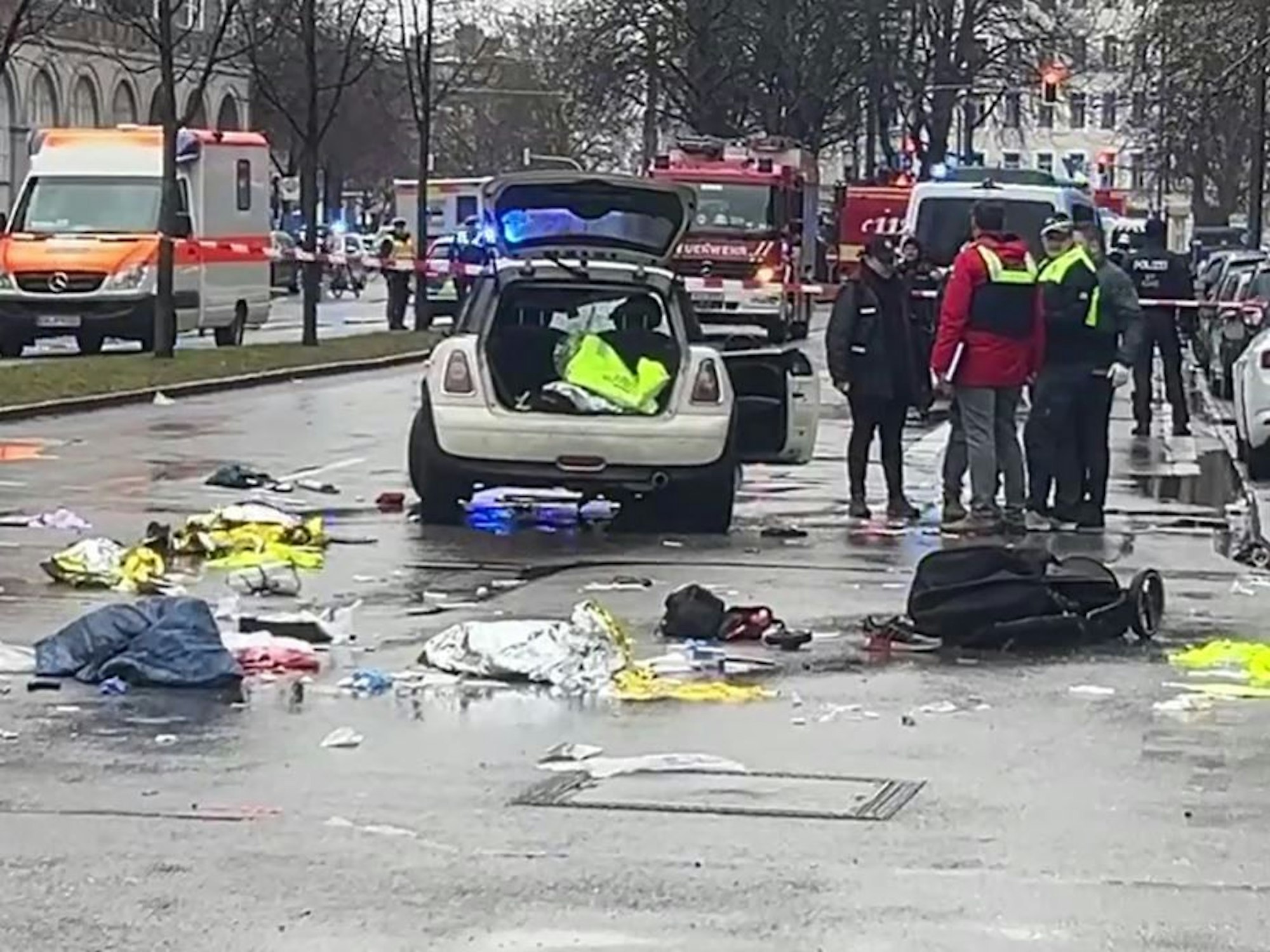 In der Münchner Innenstadt ist ein Fahrzeug in eine Menschengruppe gefahren. Polizisten untersuchen ein Auto in der Nähe des Einsatzortes.