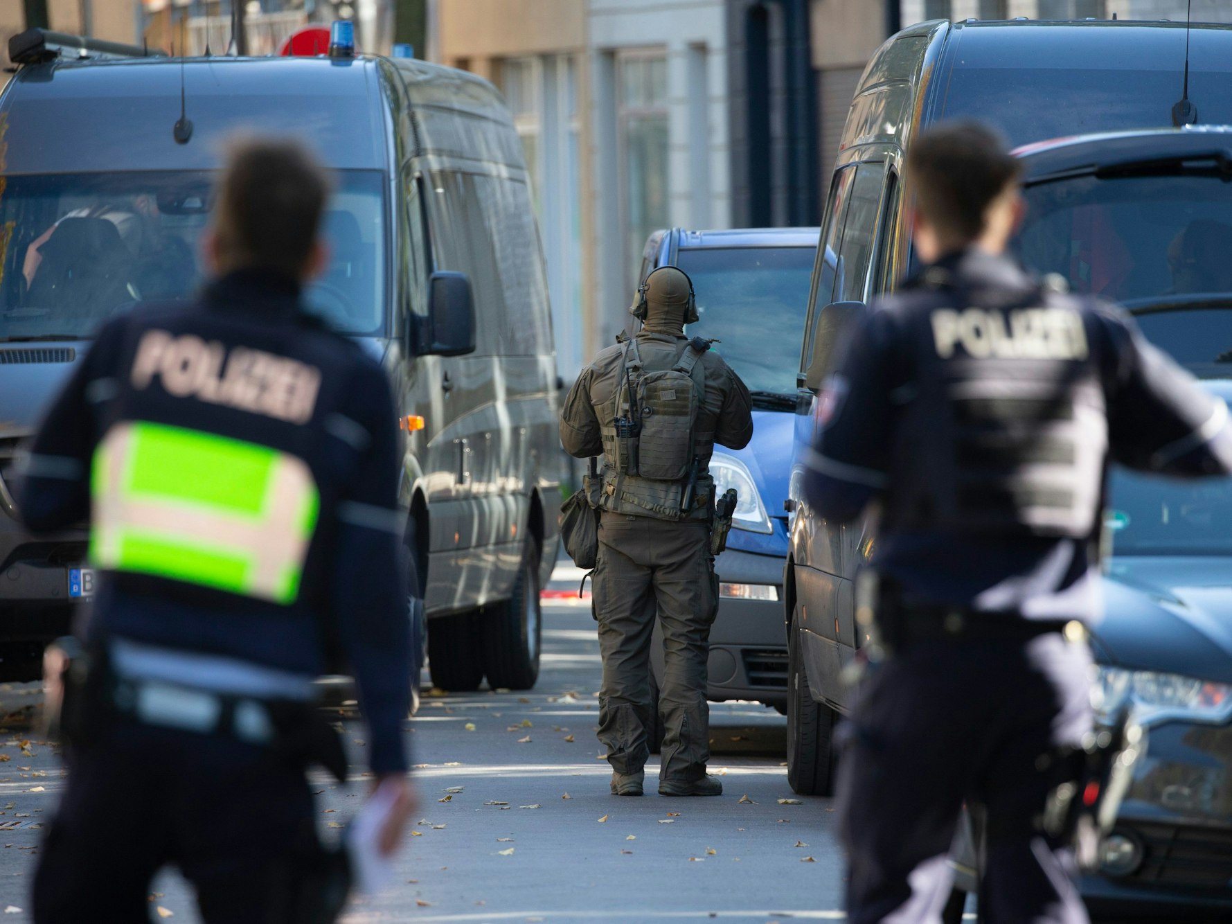 Beamte eines Spezialeinsatzkommandos stehen vor einem Mehrparteienhaus im  Stadtteil Mülheim.