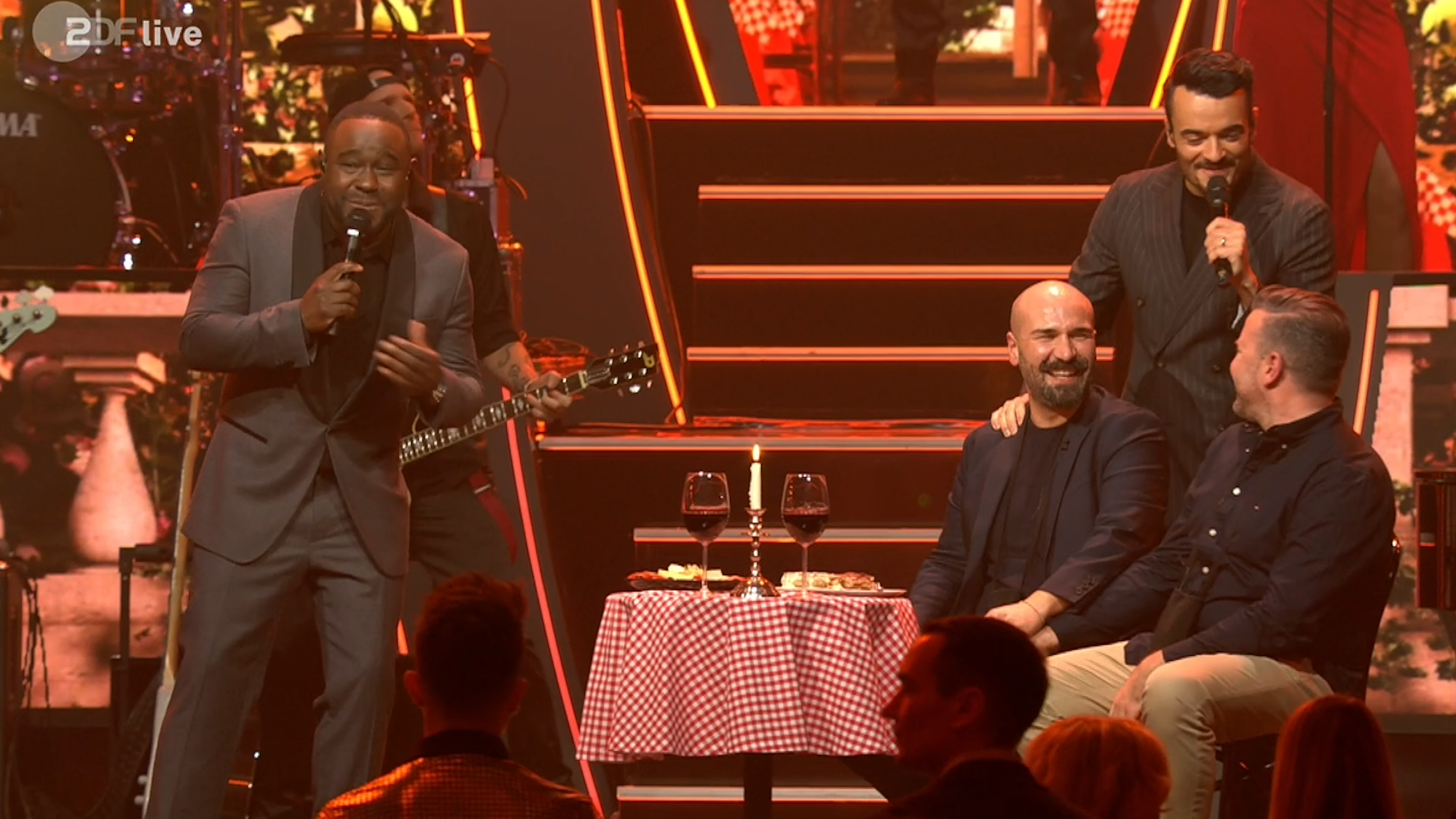 Starkoch Nelson Müller (l.) sang in der „Giovanni Zarrella Show“ am 15. Februar 2025 in Friedrichshafen gemeinsam mit dem Moderator für das künftige Ehepaar Pino und Stefan (v.l.).